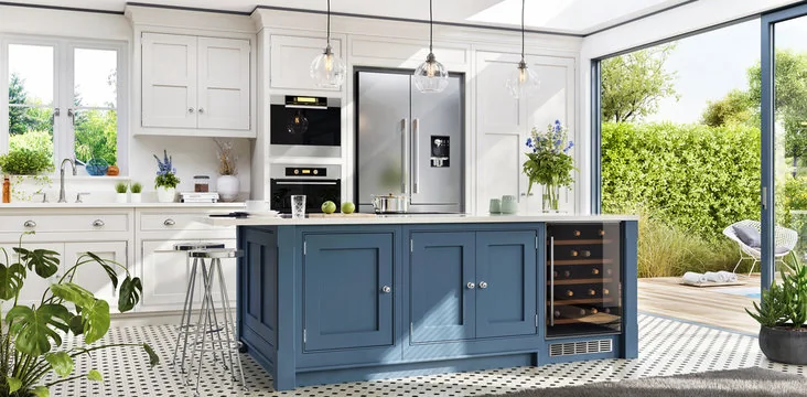 White shaker kitchen with blue island and wine fridge opening to a garden
